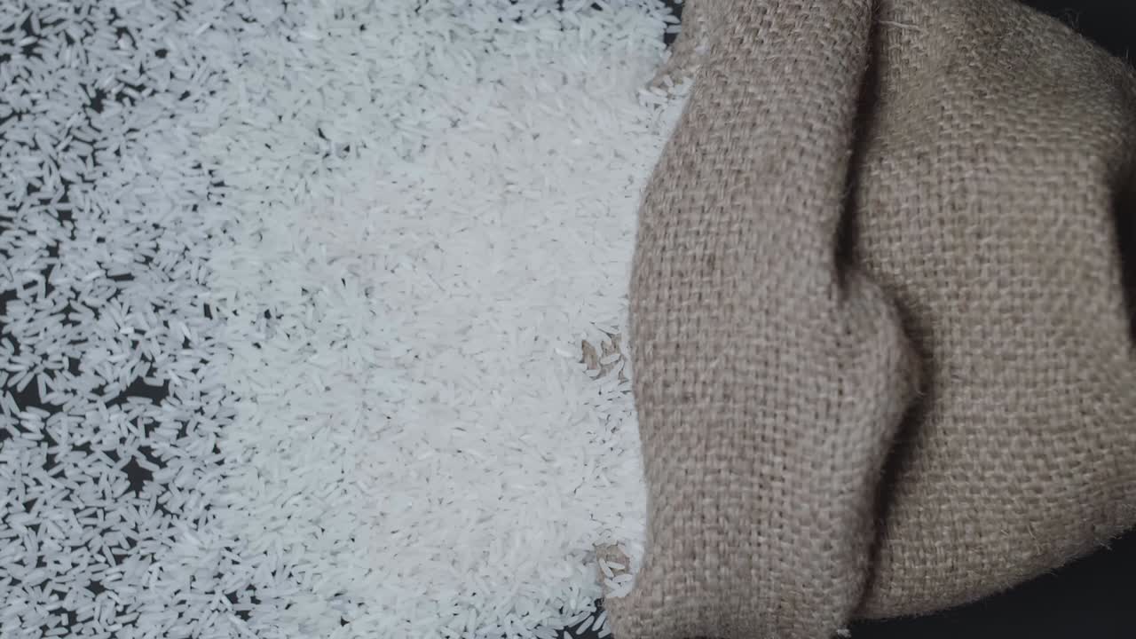 Slow Motion Rice Pours Out Of Falling Sack Over A Light Background