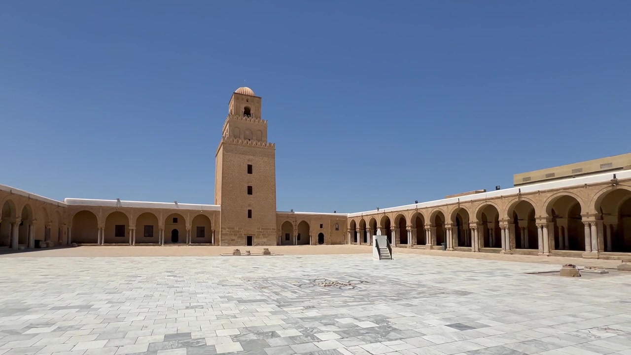 Antico cortile di moschea e torre del minareto a Kairouan, Tunisia, sotto un cielo azzurro limpido a Kairouan, Tunisia
