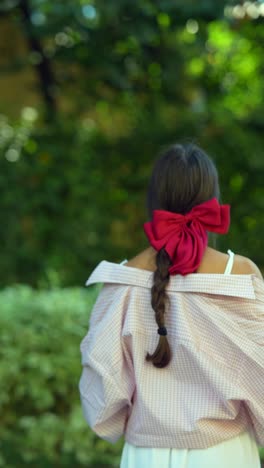 woman with red bow in park