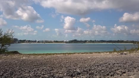 aerial view over a beach and turquoise water, towards the coast of nassau, bahamas - low, drone shot