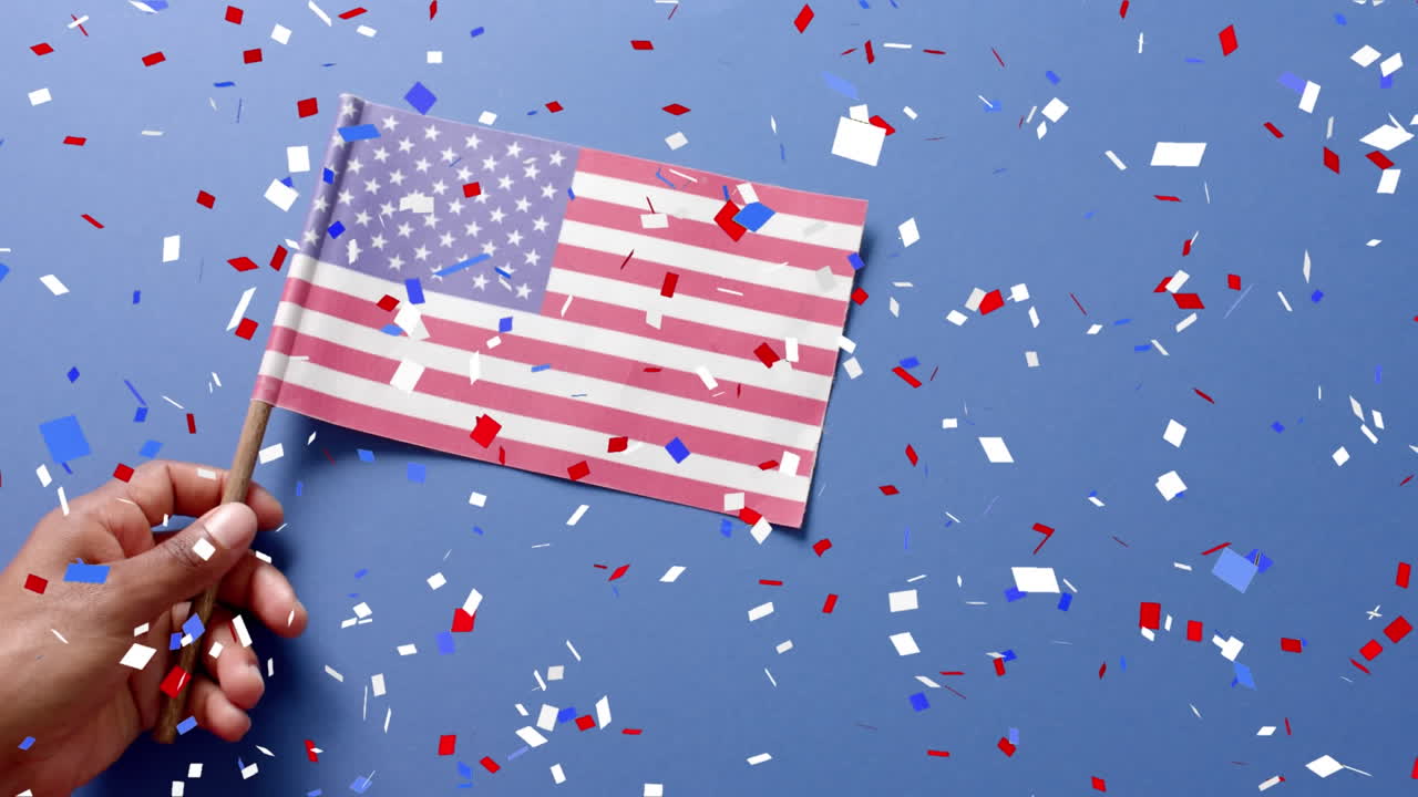 Animazione di coriandoli che cadono su una mano che tiene la bandiera degli Stati Uniti d'America su sfondo blu.