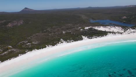 4K-Drone-video-panning-around-the-ocean-and-the-soft-white-sand-to-show-the-lush-green-landscapes-and-blue-lake-at-Thistle-Cove-Beach-in-Esperance,-Western-Australia