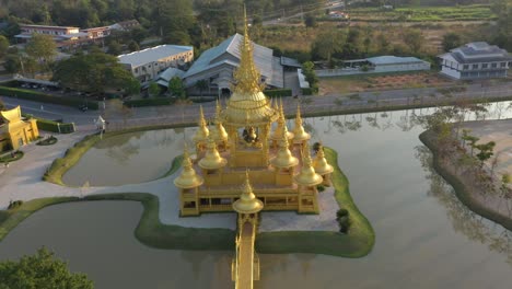 aerial drone of wat rong khun giant buddhist white temple and golden temple with mountains and scenic landscape in chiang rai, thailand