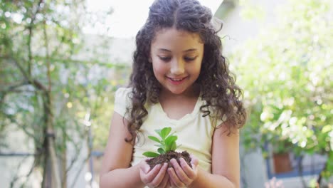 Mixed-race-mother-and-daughter-gardening-in-sunny-garden,-watering-plants