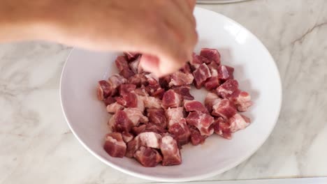 close up of adding salt on top of the chopped pork