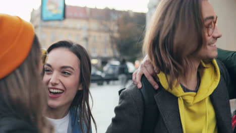 young caucasian happy couple walking the city while they friends comming up, greeting and hugging cheerfully