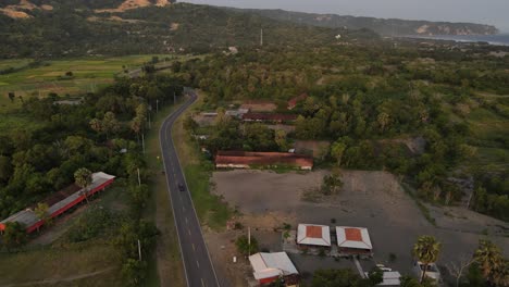 Vista-Aérea,-Camino-Sinuoso-Entre-Colinas-Y-Costa-Del-Mar