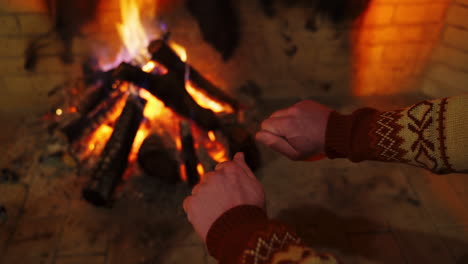 man warming hands by the fire indoors. cozy fireplace with burning wooden logs and flame warming male's hands . close-up.