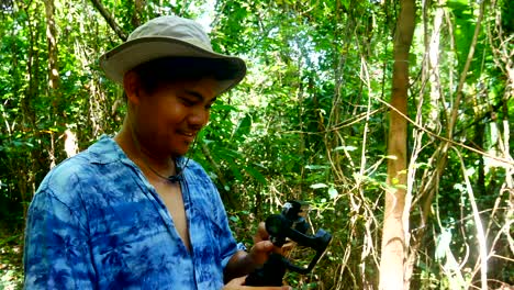 videos de viajes de bloggers de viajes o vloggers usan herramientas móviles y estabilizadoras para tomar videos durante el trekking o el senderismo en la selva tropical o los bosques tropicales, concepto de viaje
