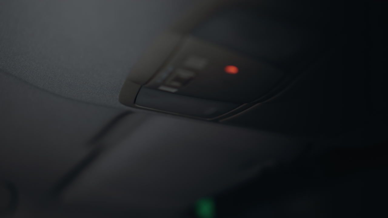 vista en primera persona de una mujer encendiendo la luz del coche izquierdo por la noche. su mano con uñas pintadas de negro es claramente visible mientras alcanza el interruptor de la luz dentro del coche