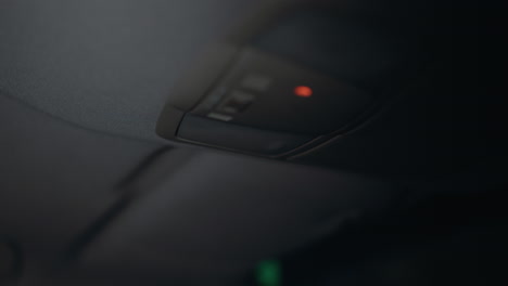 first-person view of a woman turning on the left car light at night. her hand with black painted nails is clearly visible as she reaches for the light switch inside the car