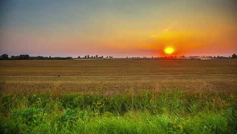 Sunset-over-wheat-fields-being-harvested-with-combine-harvesters.