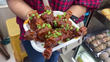 crispy chilli chicken fried with red sauce in a road side stall in kolkata.