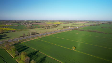 Traffic-on-the-country-road-among-green-and-yellow-agricultural-fields-daytime-in-Poland---High-up-drone-view