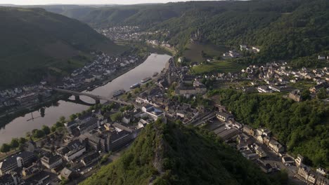 wide angle aerial dive down a steep mountain ridge towards the old town and the moselle river in cochem, germany in soft morning light