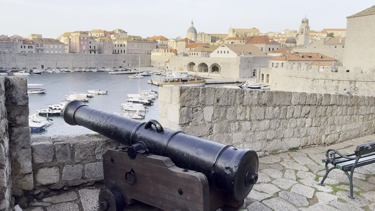 Vista sul Porto Ovest di Dubrovnik, sulle Mura della città e sugli iconici tetti in terracotta illuminati dall'alba dorata [clip di viaggio cinematica]