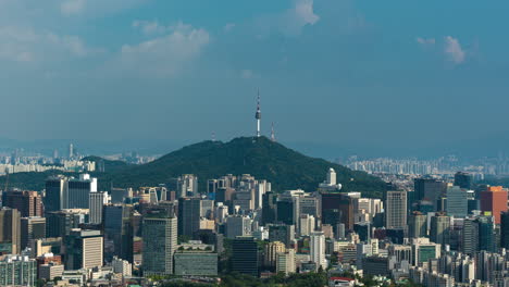 n seoul tower on namsan mountain surrounded with high business office skyscrapers and apartments - high angle view, clouds formation timelapse static