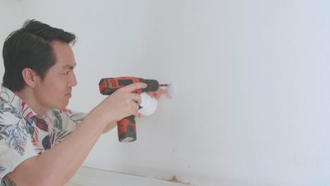 hombre asiático usa taladro eléctrico e instala cámara de cctv en la pared para la seguridad
