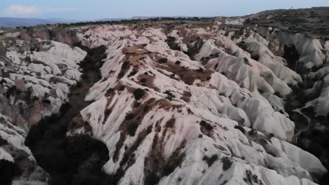 Rotación-Lenta-De-Drones-A-La-Izquierda-Sobre-El-Valle-Del-Amor-Que-Revela-Un-Camino-A-Través-De-Las-Colinas-Blancas-Durante-La-Puesta-De-Sol---Kapadokya