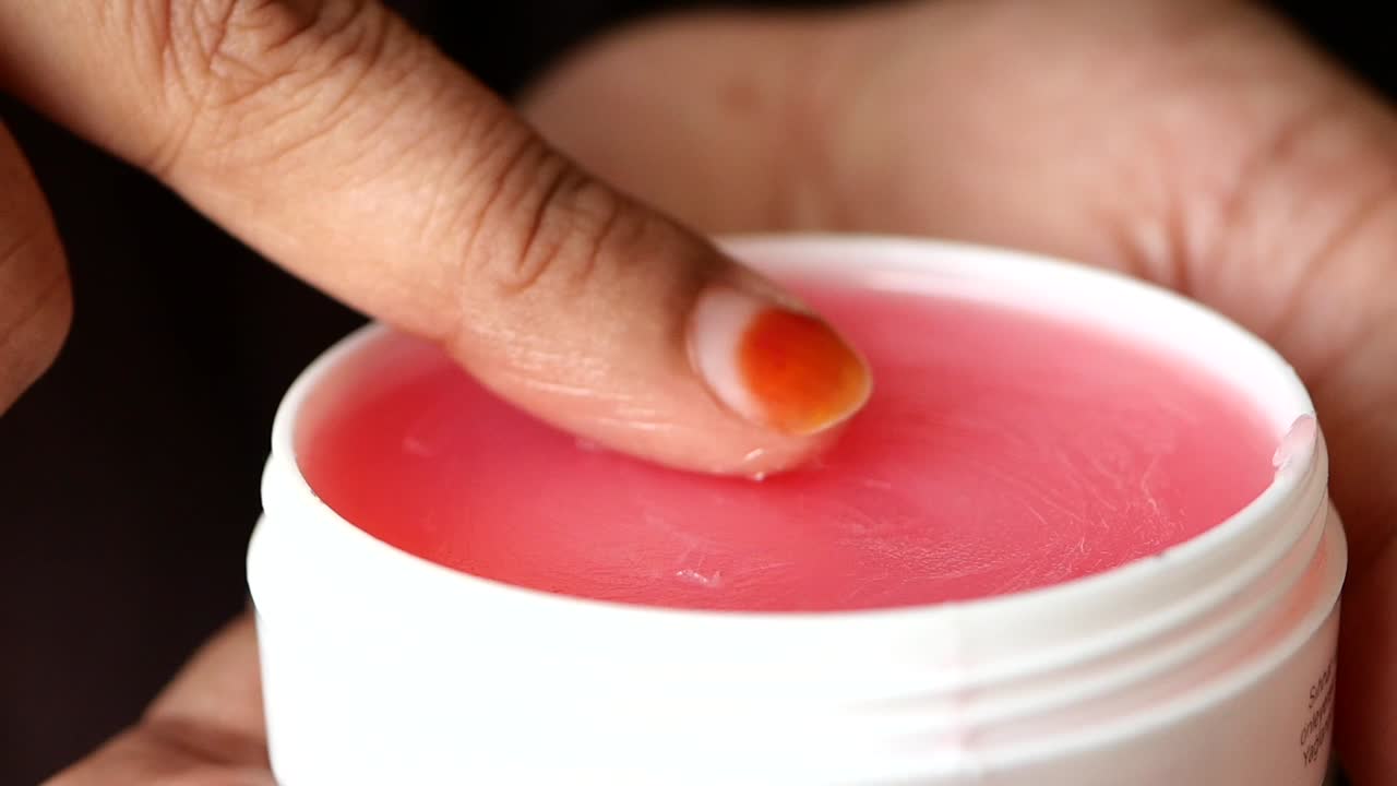 Donna che applica un balsamo labbra rosa