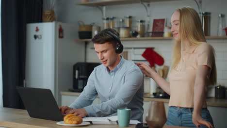 girlfriend dancing boyfriend kitchen. woman have fun with man working on laptop.