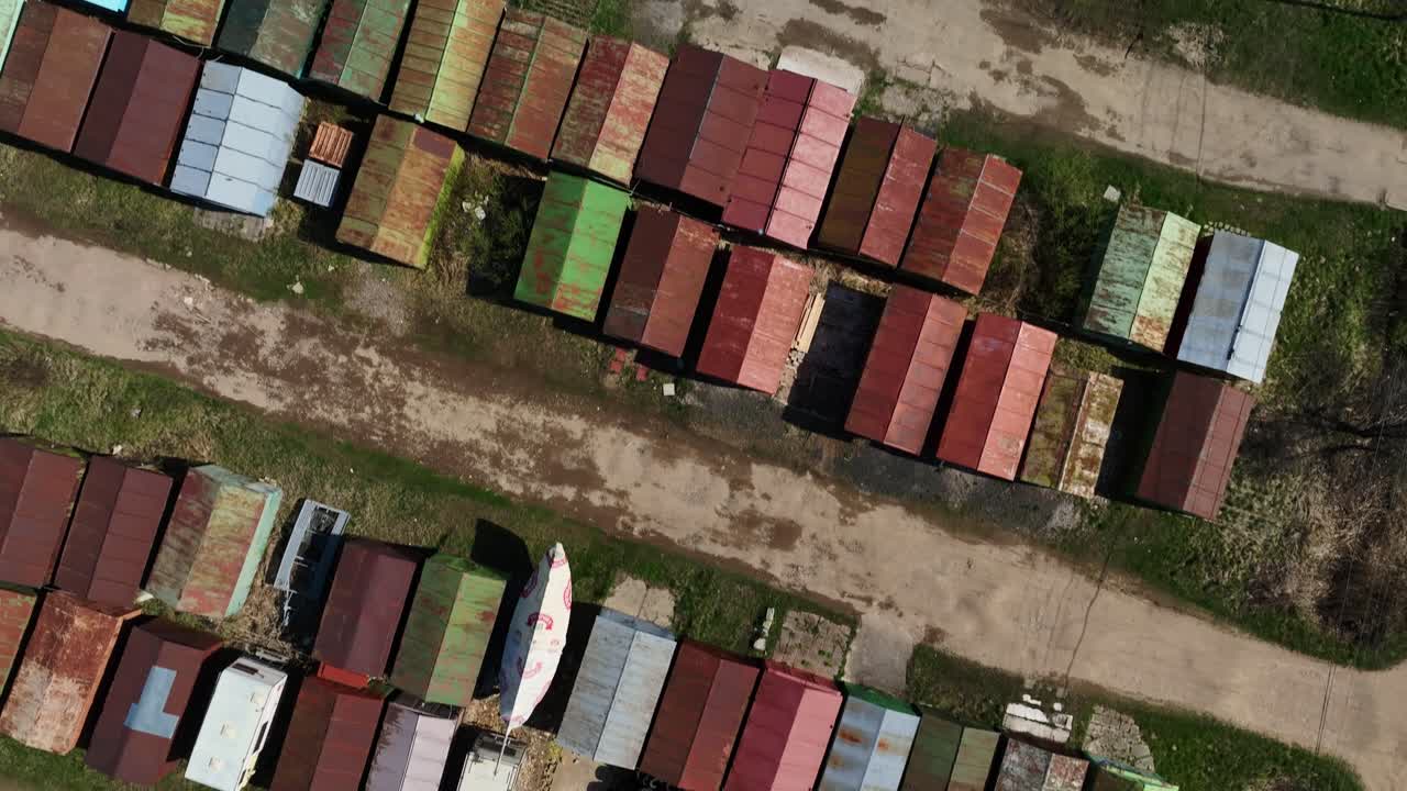vista superior de una serie de garajes metálicos donde las personas guardan una amplia variedad de coches usados y otras propiedades