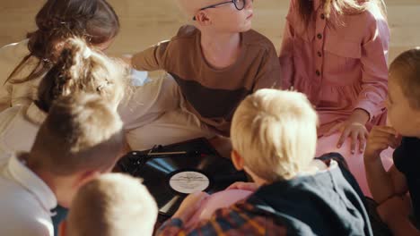 interested preschool children turn on the record player and listen and examine it carefully in the room for preparing children for school