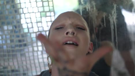 young woman with tattoos and a shaved, bald head is dancing with passion and energy in a sensual and powerful way