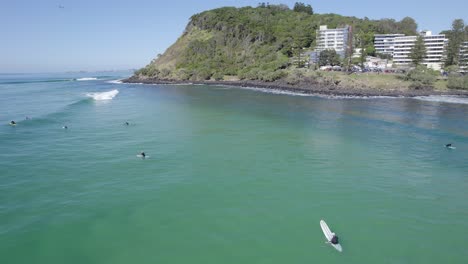 surfers on surfing boards floating in the sea near burleigh hill in gold coast, queensland