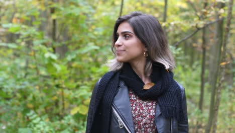 Brunette-girl-in-forest-is-looking-on-the-side-and-leaf-is-falling-down-from-the-tree