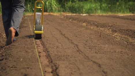 primer plano de una sembradora manual plantando semillas en el suelo, granjero descalzo trabajando, copiando espacio