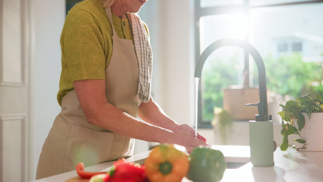 Donna matura che si lava le mani in una cucina luminosa prima di cucinare