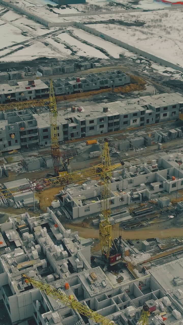non-operating construction ground with high yellow cranes surrounded by wasteland at early twilight aerial view
