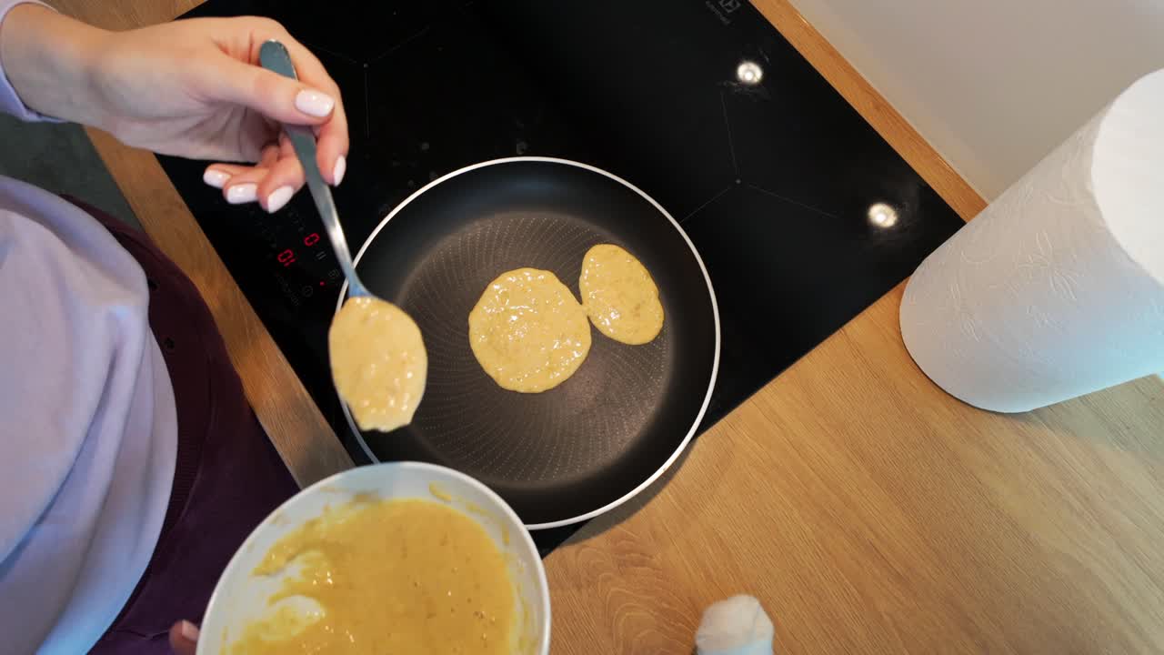 fotografía superior de una mujer preparando panqueques en la cocina en casa por la mañana para el desayuno
