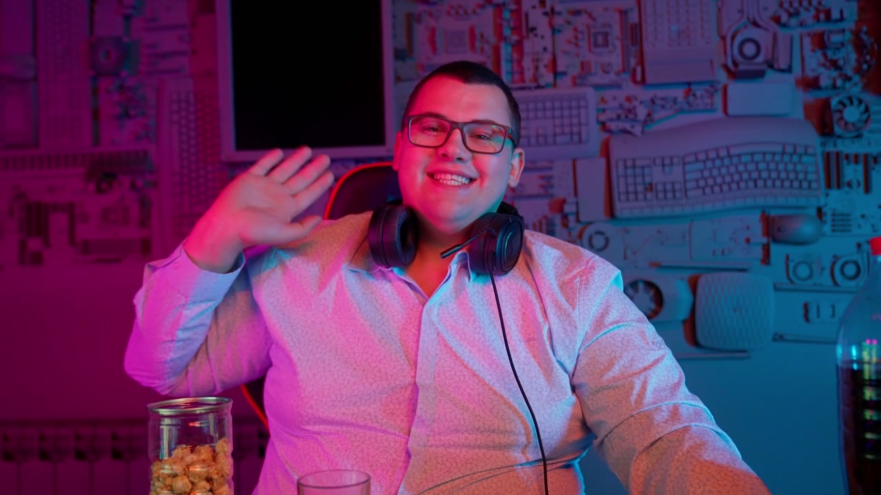 Giovane gamer felice che saluta e sorride in una stanza illuminata al neon