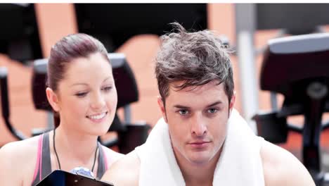 Animation-of-smiling-female-fitness-coach-and-man-exercising-at-gym