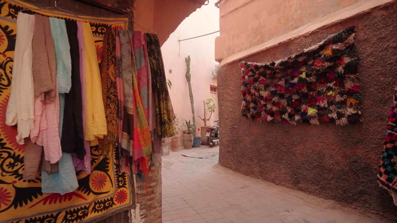 Brightly colored scarves and fabrics hang on display inside a Moroccan market alley