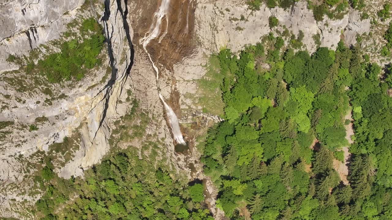 Aerial drone view of Seerenbachfälle waterfall flowing down cliffs in lush Swiss alps forest near Walensee