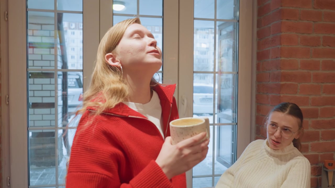 To unge kvinder taler og drikker kaffe på en hyggelig café