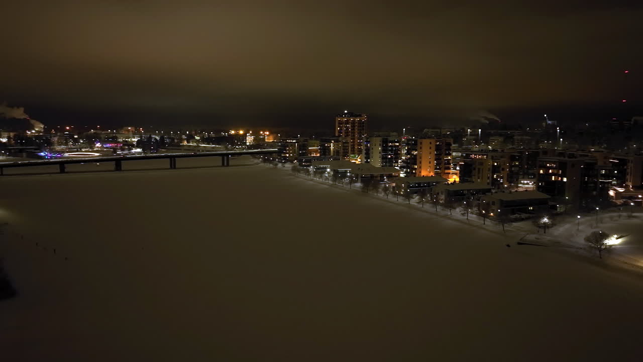Aerial view rotating over the Pielisjoki river, winter night in Joensuu, Finland