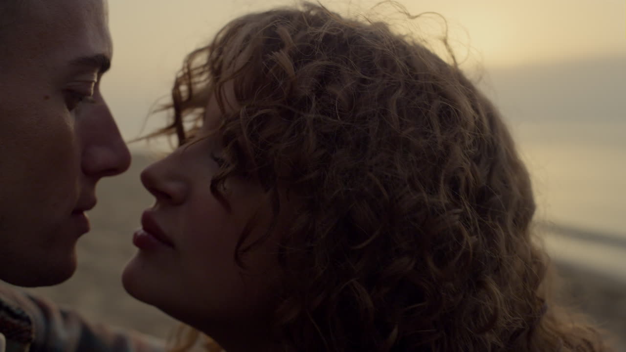 pareja romántica besándose en la playa al atardecer. cara de mujer coqueteando con hombre en una cita