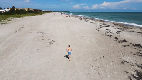 Junger-Erwachsener-Mann-Läuft-Und-Trainiert-Am-Strand-Von-Florida,-Luftaufnahme