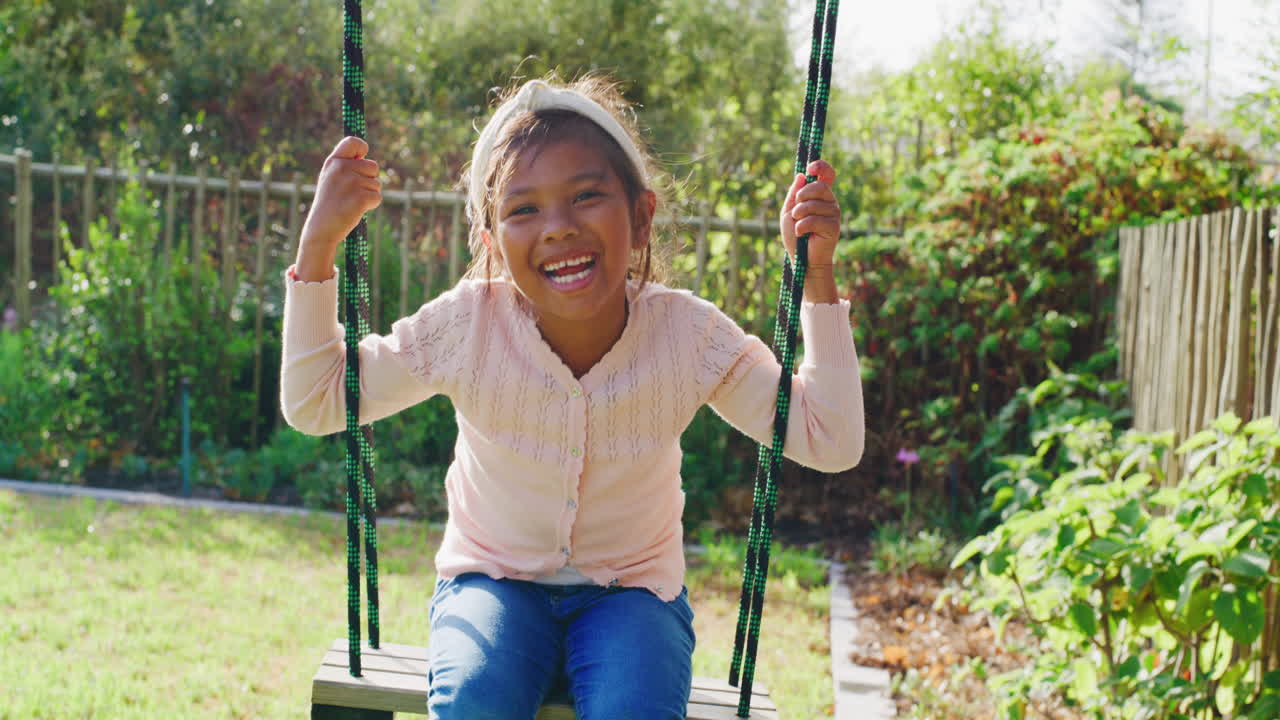 chica balanceándose en un jardín
