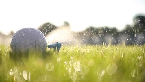 Ein-Erfolgloser-Golfschläger-Schlägt-Einen-Golfball-In-Superzeitlupe.-Nach-Dem-Aufprall-Steigen-Morgentautropfen-Und-Graspartikel-In-Die-Luft.