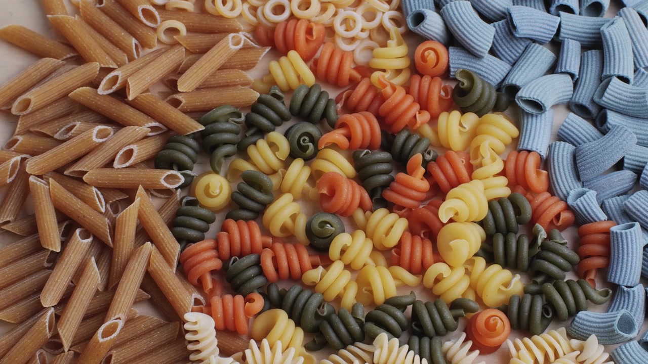Assortment of Colorful Uncooked Pasta Varieties on a Wooden Surface