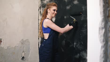 Attractive-woman-enjoying-the-process-of-painting-her-wall-with-the-roller.-Side-view