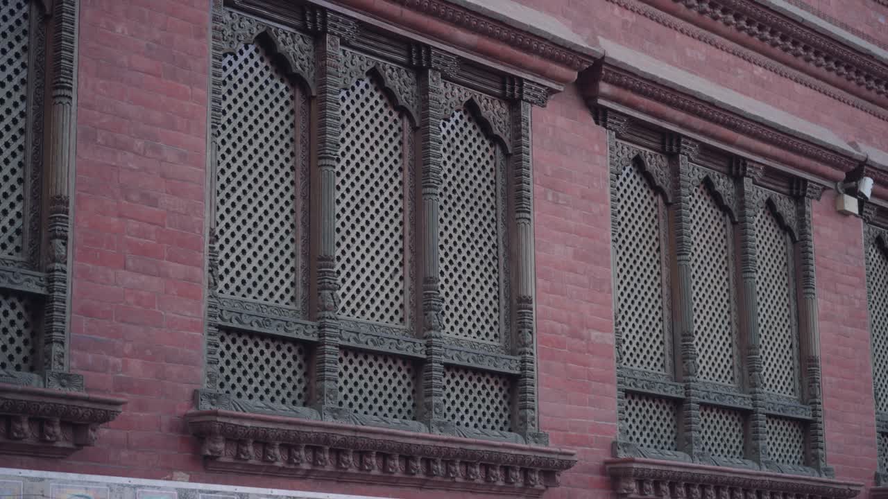 Red Brick Walls With Nicely Carved Wooden Windows Of An Old House In Kathmandu, Nepal - Low-Angle Shot