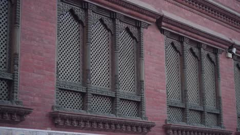red brick walls with nicely carved wooden windows of an old house in kathmandu, nepal - low-angle shot
