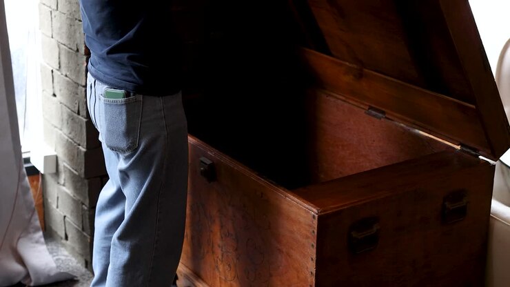 Una persona apre il coperchio di una grande cassa di legno accanto alla finestra, luce naturale, telecamera stabile