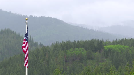 the united states flag flys over the idaho mountains on a wet afternoon